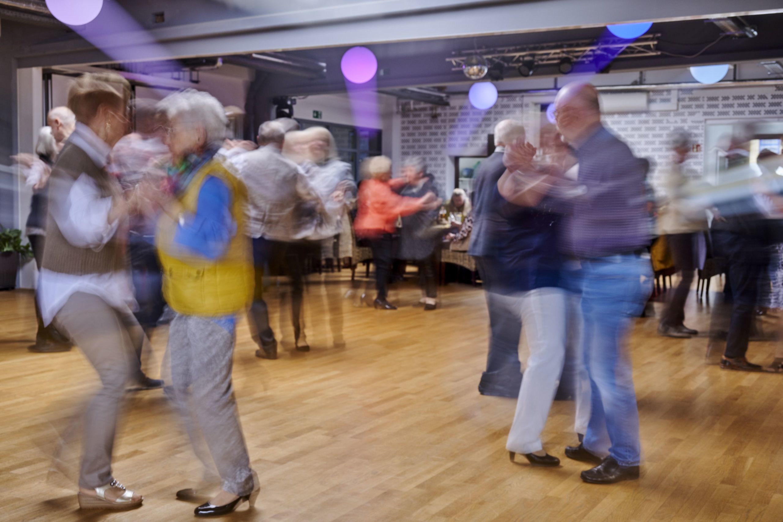 Senioren, die paarweise in einem großen Raum miteinander tanzen